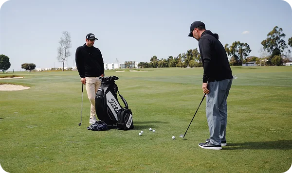 Two golfers practice shots around the green.